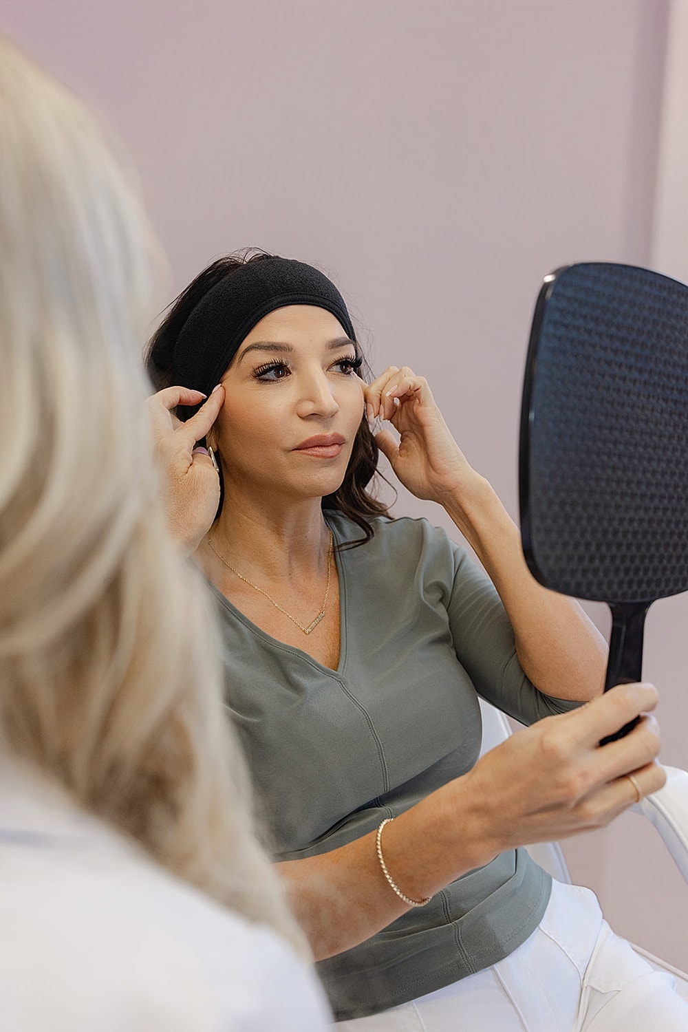 Woman examining her face in a mirror.