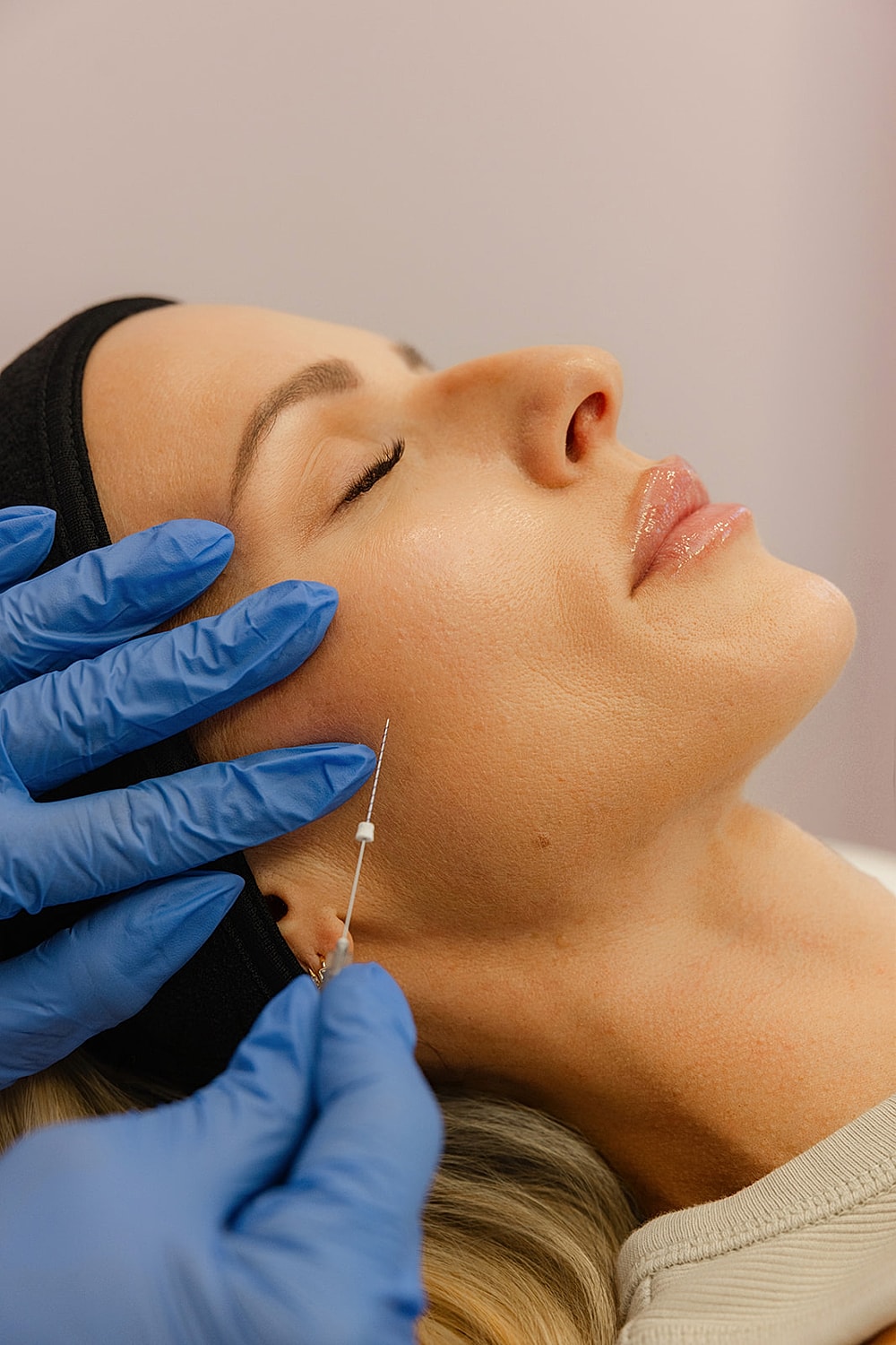 Cosmetic procedure with syringe on woman's face.